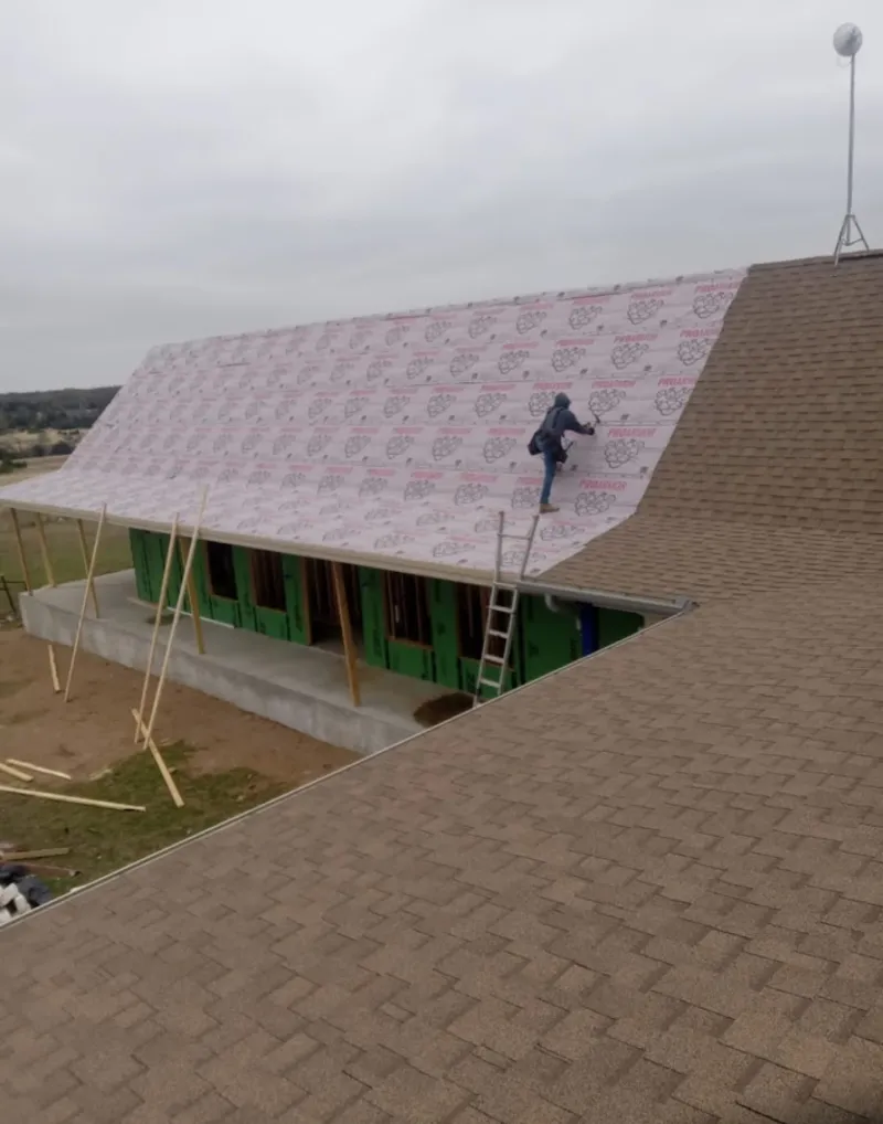 Worker preparing underlayment for a metal roof installation in Ammon